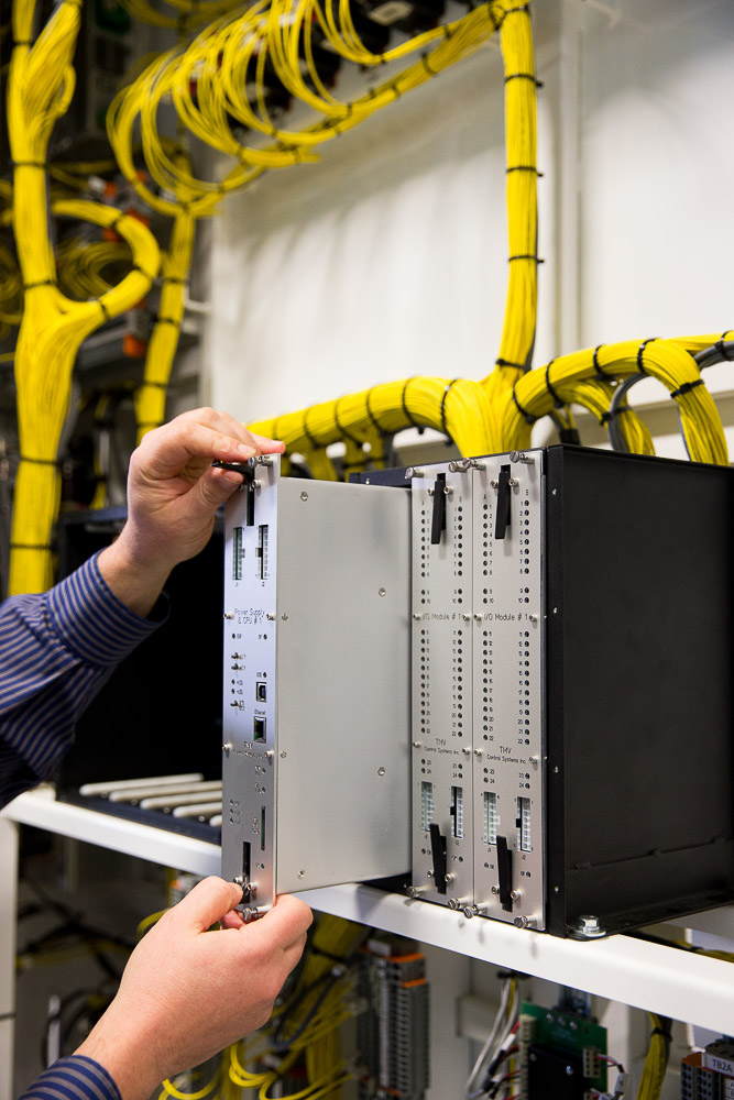 Man removing a module of the TECU control system to illustrate easy removal and installation. main electrical cabinet in background.