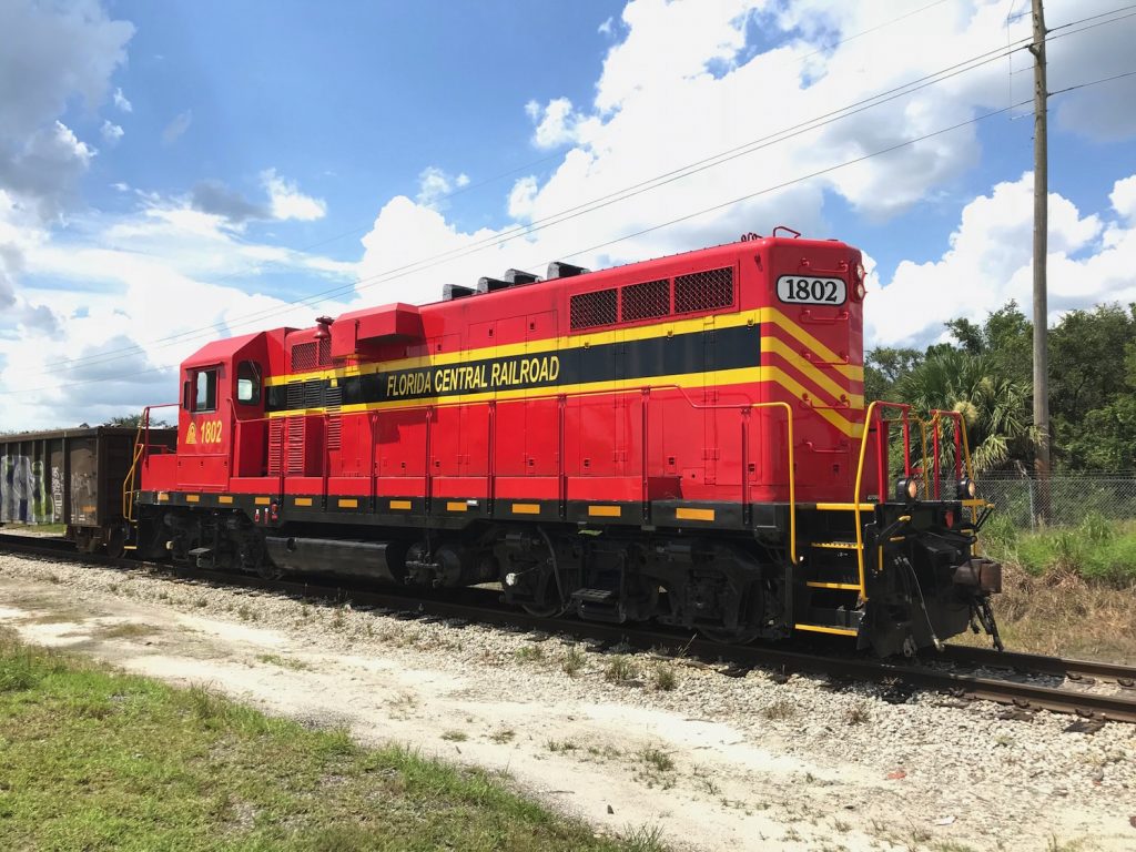Florida Central locomotive #1802 GP11 blue sky with clouds and palm trees in the background