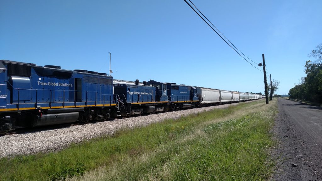 Blue TGS GP35 passing through the countryside, perspective looking down country road and down tracks